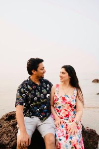 A couple enjoys a romantic moment sitting on rocks by the serene beach.